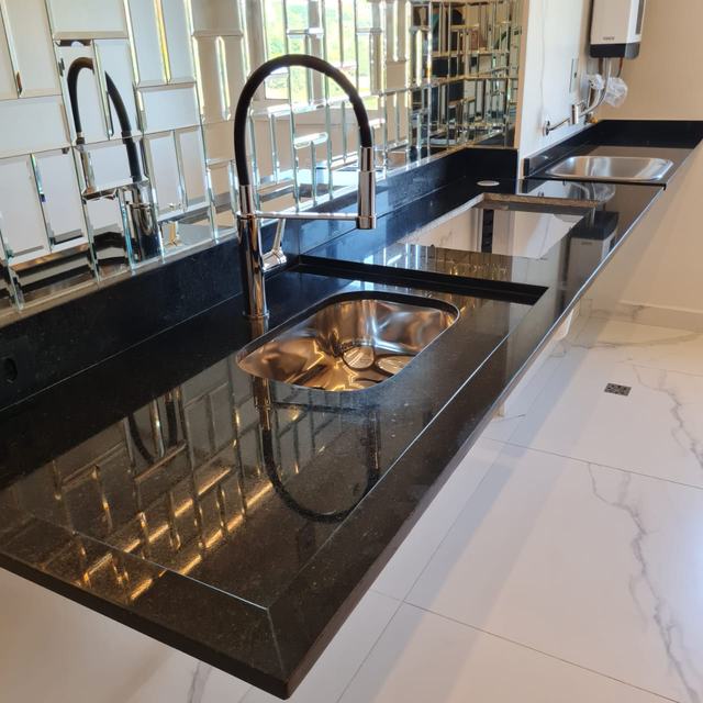 Bancada longa de granito preto com cuba dupla de inox